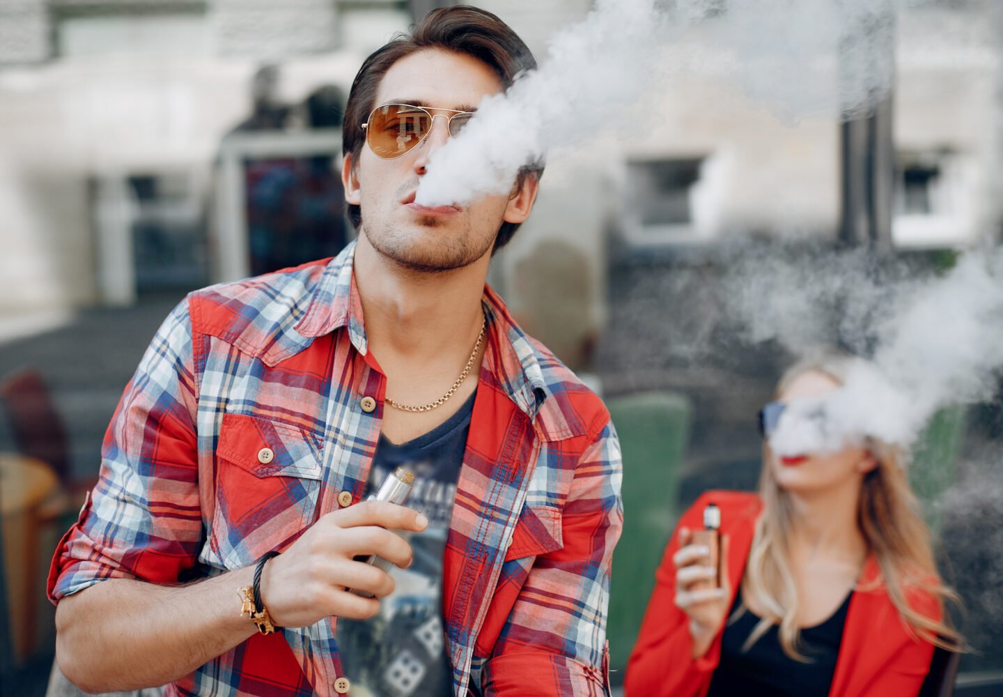 Stylish couple in a city. Two people use the electronic cigarette