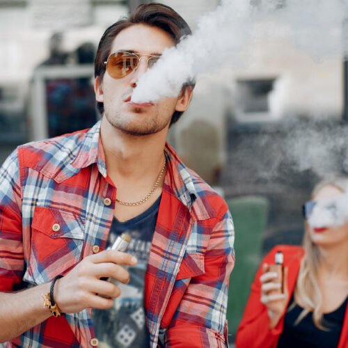 Stylish couple in a city. Two people use the electronic cigarette